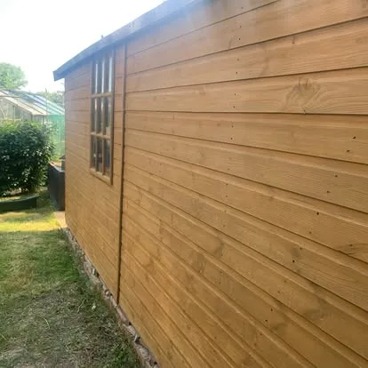 Fixed garden-building window surrounded by renewed shiplap cladding